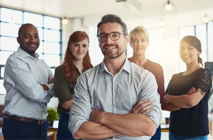 Imagen de una directiva sonriente con su equipo al fondo.